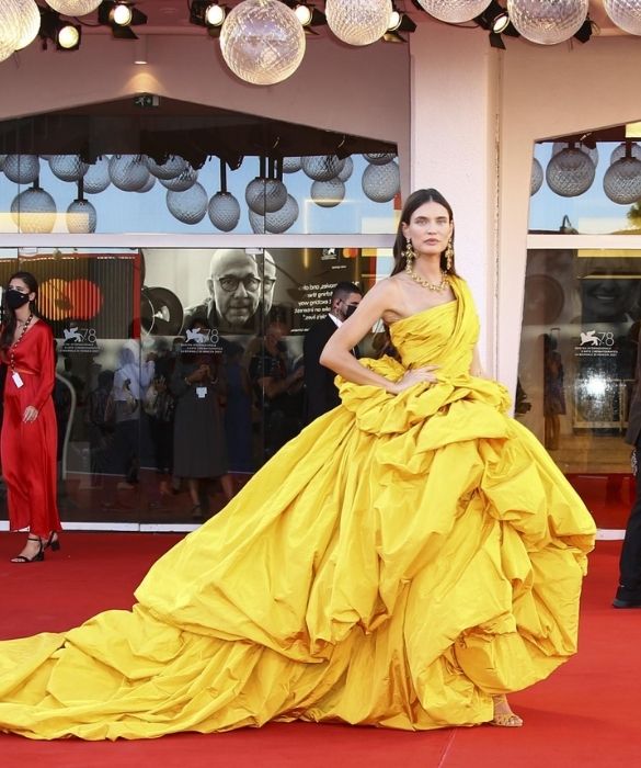 <p>La musa di <strong>Dolce&Gabbana</strong> sembra un sole dorato, nel suo monumentale abito giallo monospalla. Volumi esagerati e lungo strascico per un sontuoso capo <strong>haute couture</strong>, composto da drappeggi asimmetrici e balze stropicciate. Il massimalismo al suo massimo splendore, anche grazie agli importanti <strong>gioielli</strong>: grandi orecchini a croce e collier, accomunati da maxi gemme quadrate. Per brillare come nessun’altra.</p>
