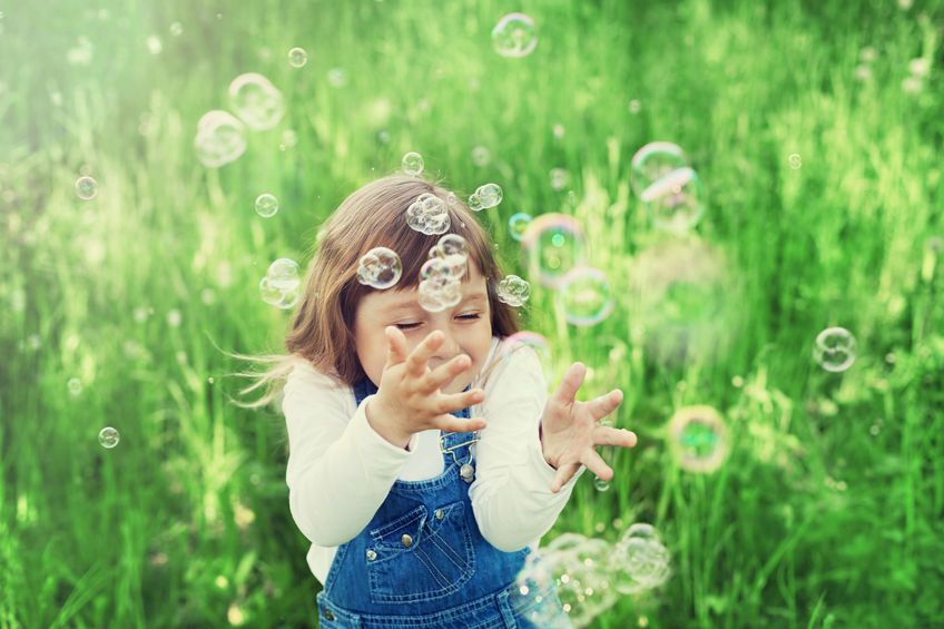 Bambina nel prato con bolle di sapone